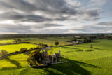 aerial view of the abbey ruins under a cloudy sky, and the surrounding field landscape visible to the horizon