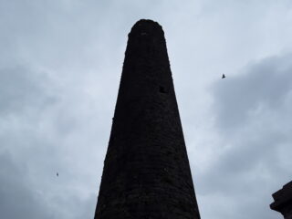 a below shot looking up toward the top of the round tower, piercing the dark grey sky.