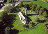 aerial view of a church and round tower within an enclosed complex.