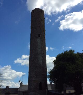 the round tower is backdropped by a bright blue sky, with a few clouds dispersed.