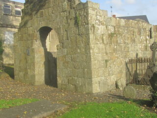 the remaining ruins of a roofless church, with an open arched doorway.