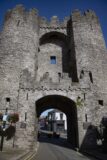 a castle-like facade with an arched gate, with a road cutting through it