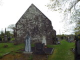 view of the end wall of the church, with two small window slats in the centre.