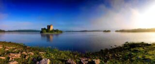 panoramic view of the castle on the lough, the sun reflected in the water.