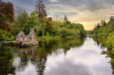 a picturesque view of the trees reflected in the river, with the ruins of the small fishing house on the river's edge