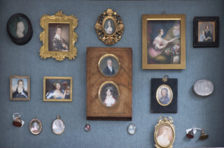 a collection of miniature portraits hung on a blue wall
