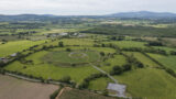 aerial view of the ringfort, a stone fort inside a hillfort. A walkway from the car park leads to the fort.