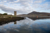 wide view of the castle by the water, with the hills across the water from it.