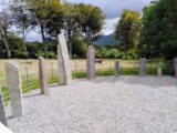 view of some of the ogham stones, in a circle, within a gravel, fenced, enclosure