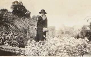 black and white image of a woman standing in a field of flowers