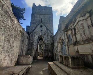 view of the tower of the church, and internal tomb sculptures on the walls.