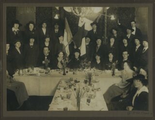 group image of mainly women, and a few men, gathered behind a large table for a photograph