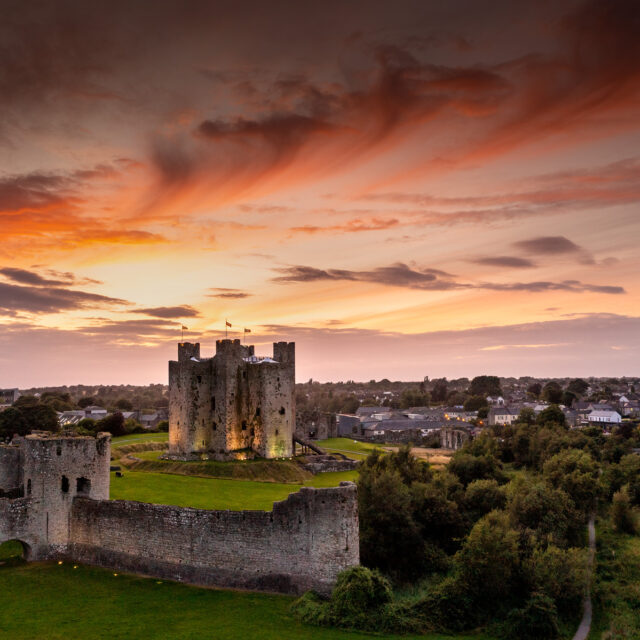 aerial view of trim castle, with a deep orange sunset filling the sky above.