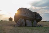 smaller stones hold up a larger capstone. The sun glints off the left edge of the capstone.