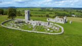 aerial view of the walled monastic site, with graves inside the walls, and another roofless building outside the walls.
