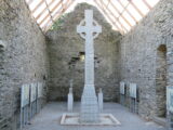 A full view of the high cross, standing within the interior ruins of a church