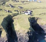 aerial view of a rocky headland with cottages and building ruins dotted across the land
