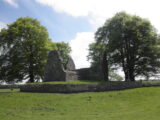 view of the church ruins, framed by two large trees on either side