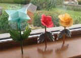 Three paper origami flowers sit on a window sill