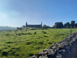 distant view of the roofless church, backlit by a clear blue sky