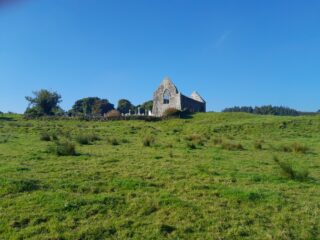 distant view of the church ruins, with headstones just beside it