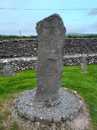 an inscribed stone cross standing on a stone raise