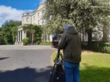 A man swith an easel stands to the side of farmleigh