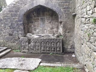a stone tomb, with carved figures on top of it