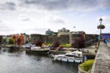 the castle beside the water with small boats docked