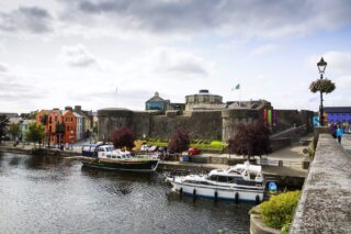 the castle beside the water with small boats docked