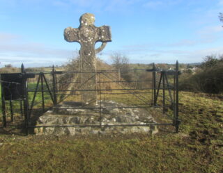the high cross, with most of its upper ring missing, protected by a small surrounding fence