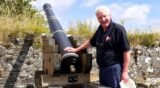 A man standing beside a cannon