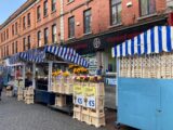 view of the street and the red brick houses, and the market stalls outside them