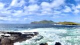 Image of a beach with mountains in the background under a blue cloudy sky