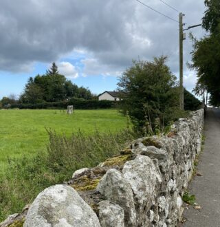 distant view of the stone within a field, beyond a stone wall