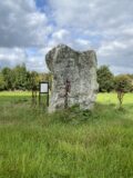 a tall and wide stone standing in a field