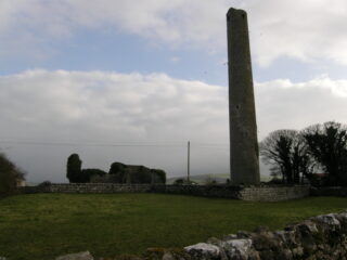 view of the round tower and church ruins backdropped by a dusky sky.