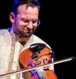 A man sits playing a violin