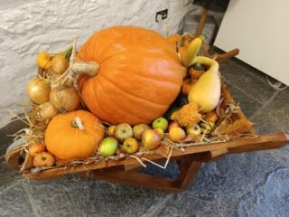 A stack of pumpkins sit on a wooden wheelbarrow.