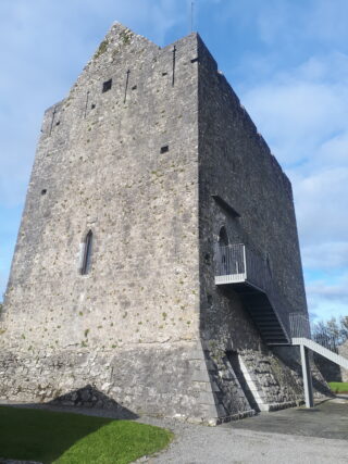 the exterior of the abbey, with steps leading up the front door, which is set high within the wall of the castle