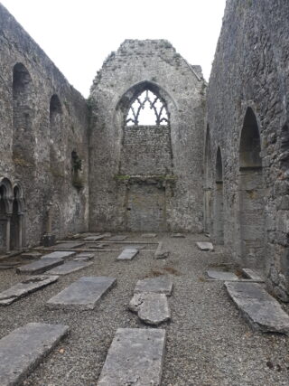 roofless interior of the abbey, with grave slabs marking the ground