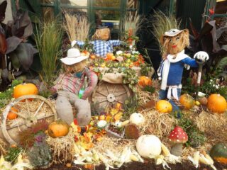 A Halloween display with scarecrows and a pile of pumpkins.