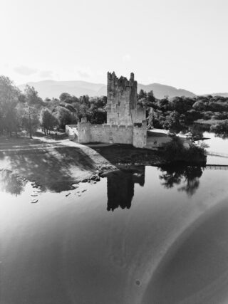 black and white image of ross castle on the water edge