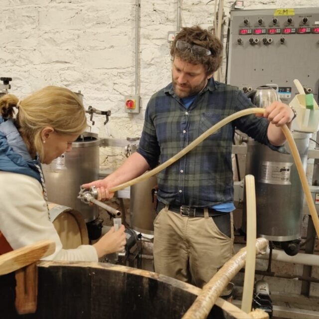 A man and lady work busily brewing