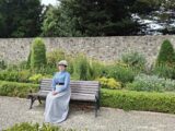 a woman sitting on a bench in victorian dress