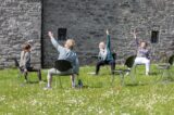 Four ladies partakig in chair yoga.