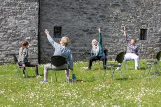 Four ladies partakig in chair yoga.