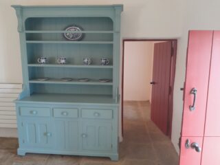 a blue sideboard beside an open door
