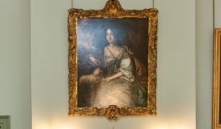 A painting hangs on a wall over a fireplace