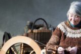 A lady spins yarn on a spinning wheel